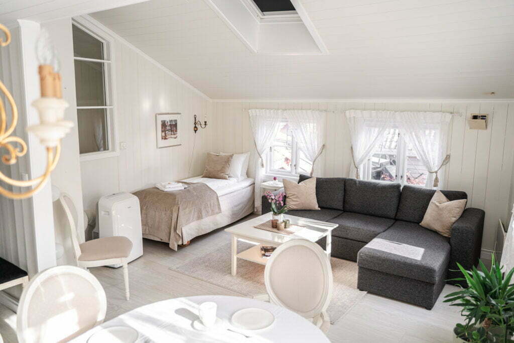 Bildet viser stue og sovekrok i Holbergsuiten - det er en sofa og en seng i bildet, samt litt av spisegruppen