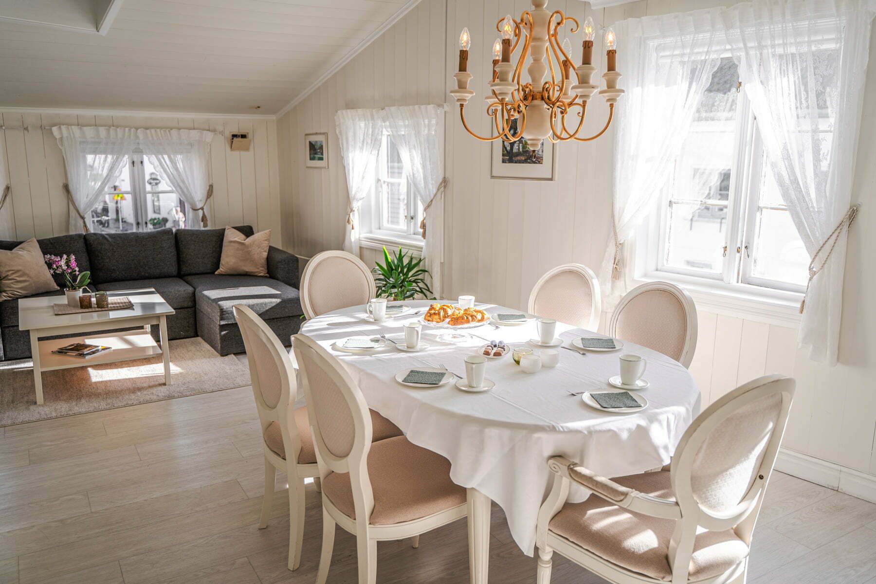 Gamlebyen Hotell Fredrikstad - Spisebord i Holbergsuiten med sofa i bakgrunn