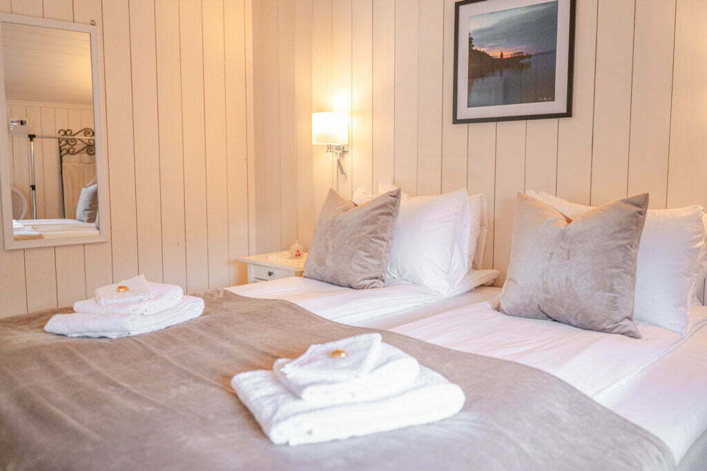 Bildet viser sengen i et soverom i Holbergsuiten - det er håndkleder på sengen, et speil på veggen og et bilde over sengen