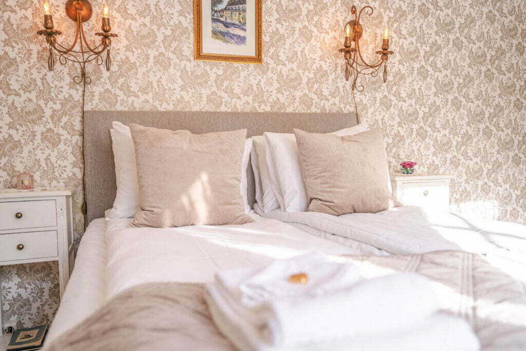 Et bilde av sengen i en av soverommene på Holbergsuiten - dobbeltseng, to nattbord og to lamper