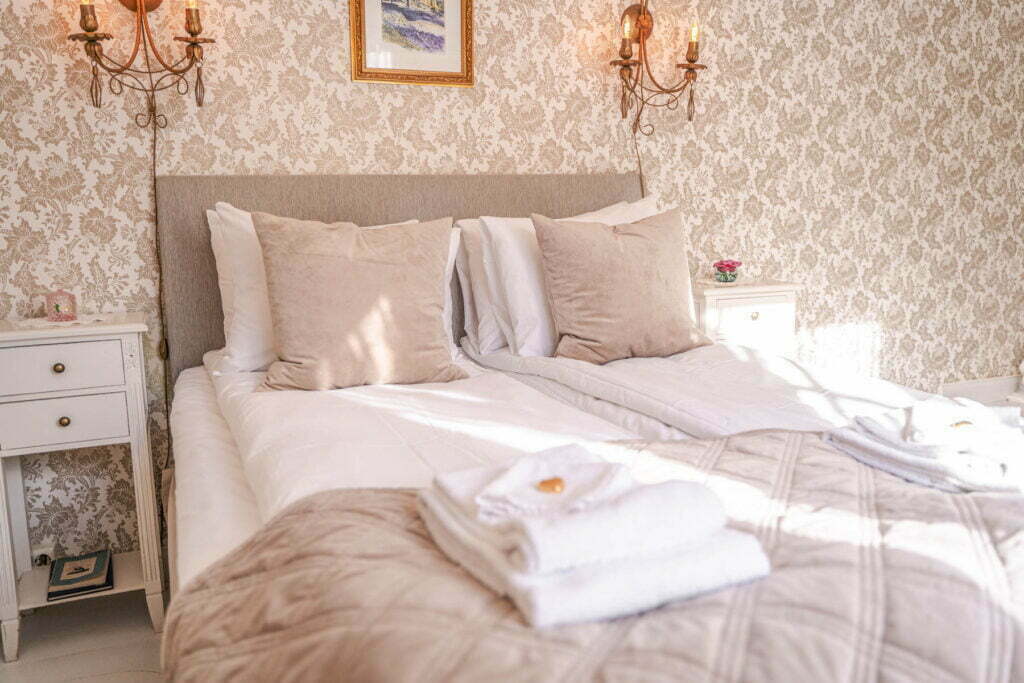Et bilde av sengen i en av soverommene på Holbergsuiten - dobbeltseng, to nattbord og to lamper