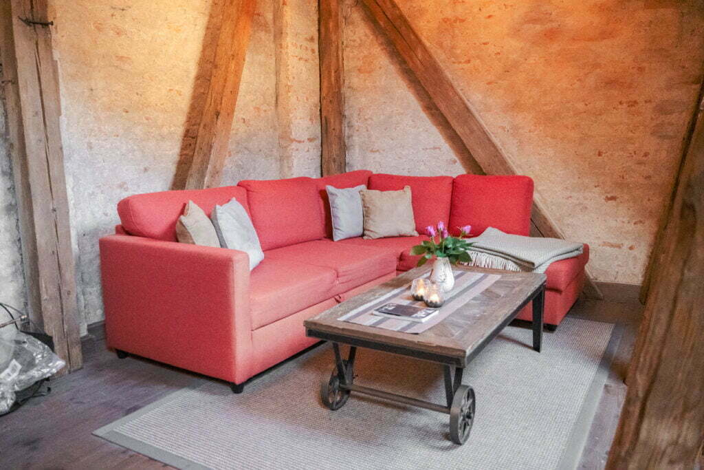 Et bilde av rød sofa i og rustikt bord i Raadhus-stallen
